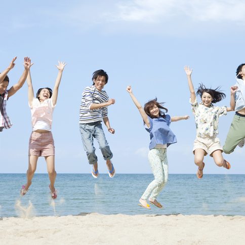 Six men and women jumping on a sandy beach